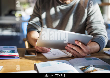 Midsection of man using tablet computer while studying at table in classroom Stock Photo