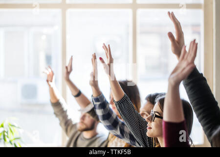Students raising hands during lesson in classroom Stock Photo