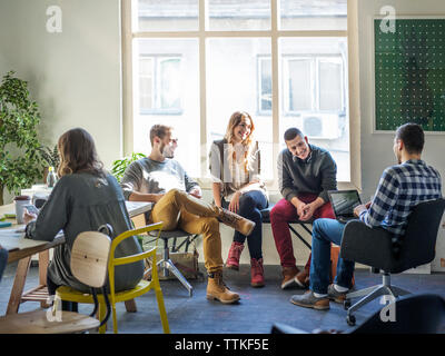 Friends discussing while sitting in classroom Stock Photo