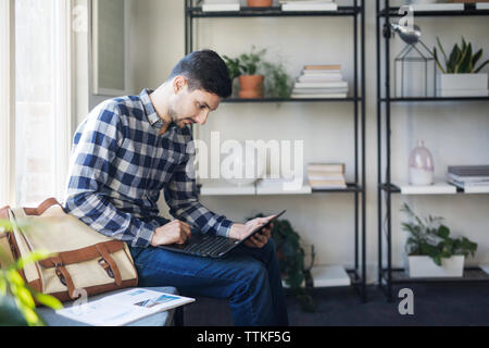 Man using laptop computer while sitting on seat in classroom Stock Photo