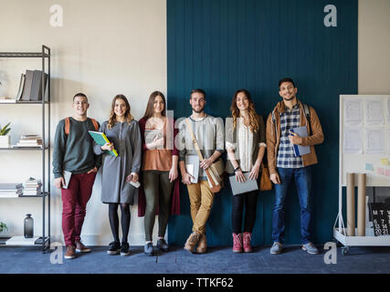 Portrait of friends standing against wall in classroom Stock Photo