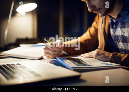 Man studying while sitting in library at night Stock Photo