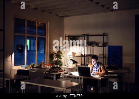 Confident student studying while sitting in library at night Stock Photo