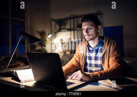 Confident student studying through laptop computer in library Stock Photo