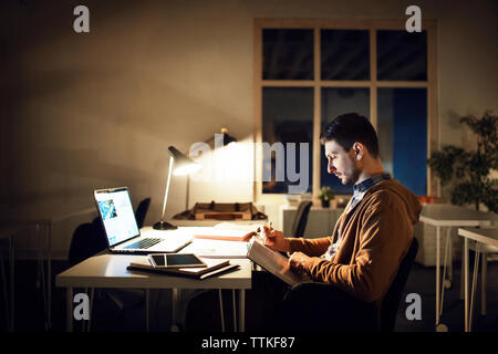 Side view of student studying while sitting at table in library Stock Photo