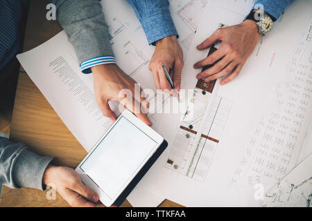 Cropped image of businessmen analyzing blueprints in office Stock Photo