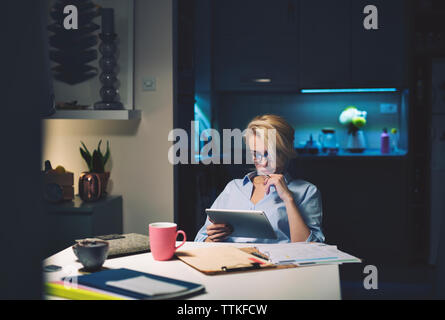 businesswoman using tablet computer while sitting at desk Stock Photo