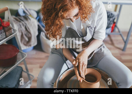 Female potter making pot with clay in workshop Stock Photo