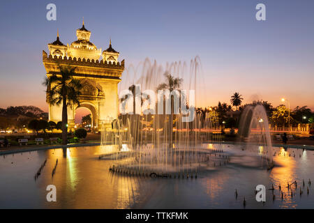 Patuxai Victory Monument (Vientiane Arc de Triomphe) and fountain floodlit at dusk, Vientiane, Laos, Southeast Asia Stock Photo