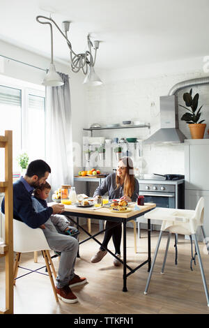 Parents with son having breakfast at table in kitchen Stock Photo