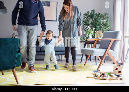 Parents assisting son in walking at home Stock Photo