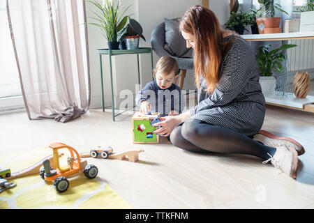 Mother and son playing with toys while sitting on floor at home Stock Photo