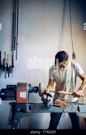 Carpenter holding chisel while shaping wooden bowl at workshop Stock Photo