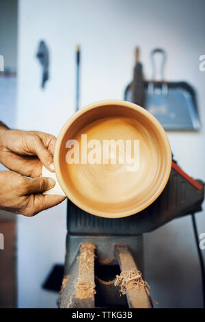 Cropped image of man making wooden bowl on machinery Stock Photo
