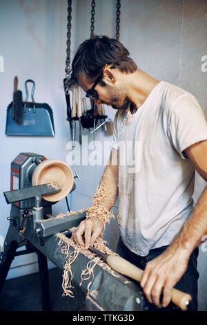 Carpenter making wooden bowl at workshop Stock Photo