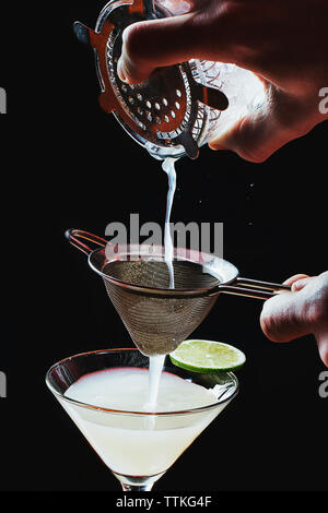 Cropped image of hands preparing cocktail against black background Stock Photo