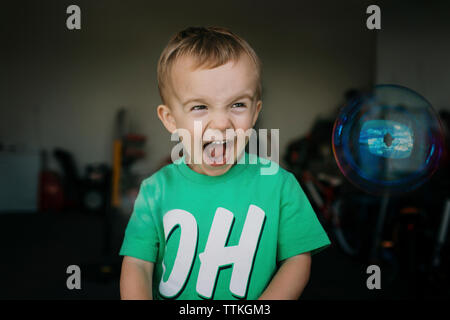 Boy looking away while screaming at home Stock Photo