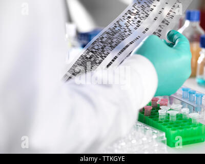 Close-up of scientist holding DNA gel by samples for testing in laboratory Stock Photo