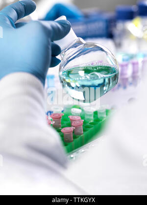 Cropped hand of scientist holding chemical in container for medical testing Stock Photo