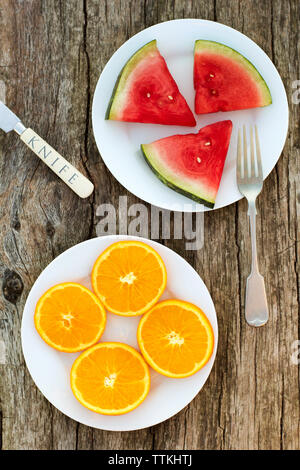 Overhead view of orange and watermelon served in plate on wooden table Stock Photo