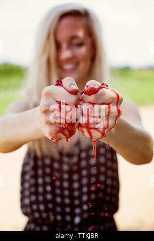 Happy woman squeezing fresh raspberries at field