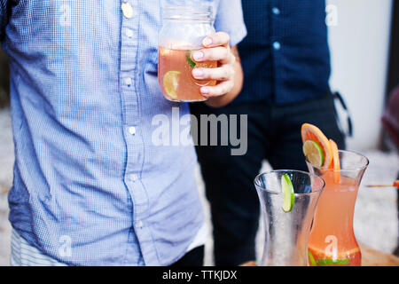Midsection of man holding drink jar Stock Photo