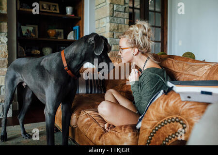 Woman looking at Great Dane while sitting on sofa Stock Photo