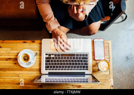 Overhead view of woman using laptop computer while sitting at restaurant Stock Photo