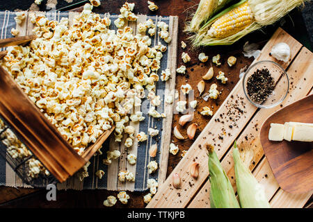 Overhead view of popcorns spilled from container on table Stock Photo