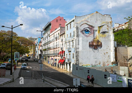 Mural of face wall painting with blue eye and nose ring piercing on the side of a building in Lisbon, Portugal Europe EU    KATHY DEWITT Stock Photo