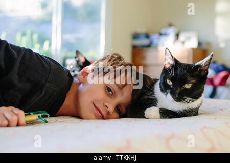 Portrait of boy and cat relaxing on bed at home Stock Photo