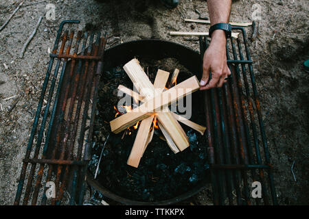 High angle view of man burning firewood in fire pit at campsite Stock Photo