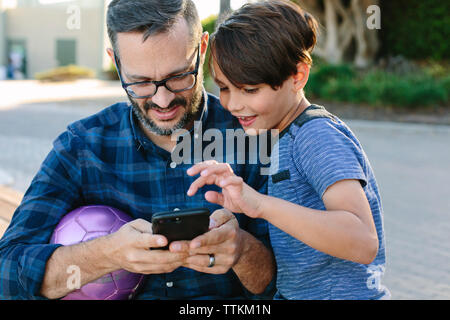 Father with son using mobile phone at park Stock Photo