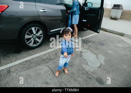 Toddler Girl Pointing And Looking At Camera In Parking Lot