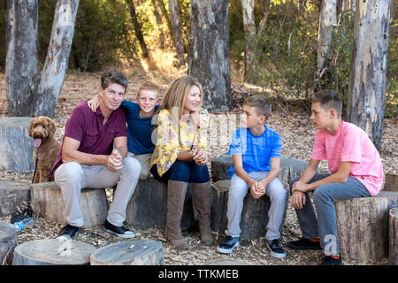 Family of five sits on tree stumps together Stock Photo