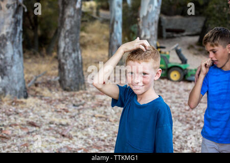 Boy with red hair and freckles touches his head and smiles Stock Photo