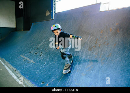 Young boy focused as he skates down a ramp Stock Photo