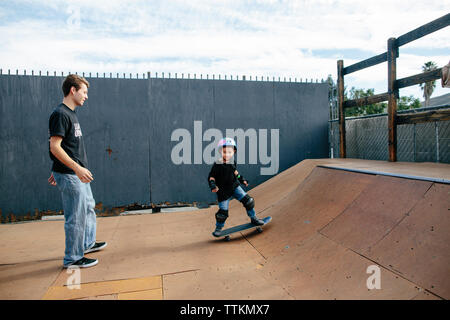 A boy with his skateboard instructor on a half pipe outside Stock Photo