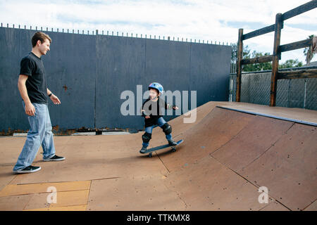 Young boy looks to his skateboard instructor while on a half pipe Stock Photo