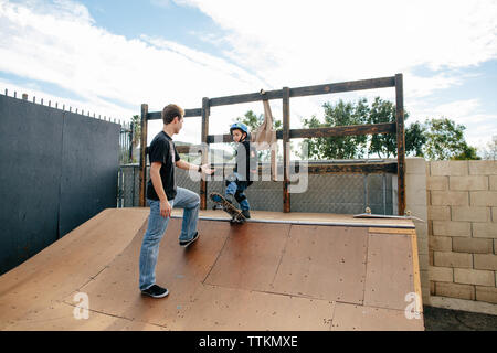 Skateboard instructor extends a hand to student on half pipe Stock Photo