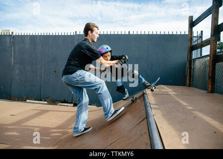 Skateboarding instructor helps student grind on half pipe Stock Photo