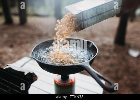 Pasta being poured in cooking utensil at campsite Stock Photo