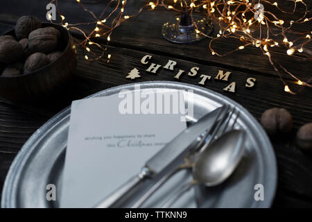 High angle view of cutleries with plate by walnuts and christmas decorations on wooden table Stock Photo
