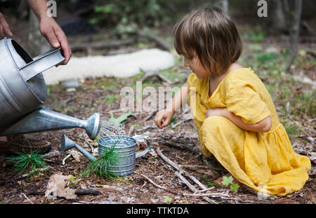 Cropped image of man pouring water in watering can for daughter Stock Photo