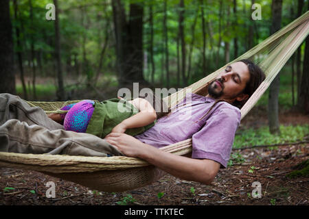 Father and daughter sleeping on hammock in forest Stock Photo