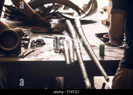 Midsection of blacksmiths working at table in workshop Stock Photo