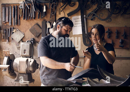 Coworkers discussing in blacksmith shop Stock Photo