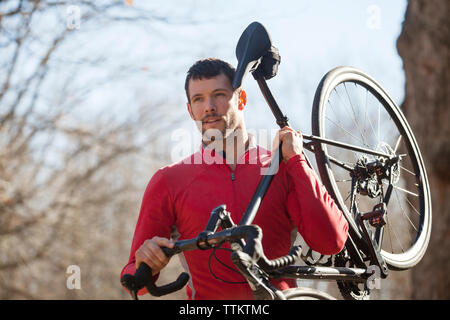 Athlete carrying bicycle in forest Stock Photo