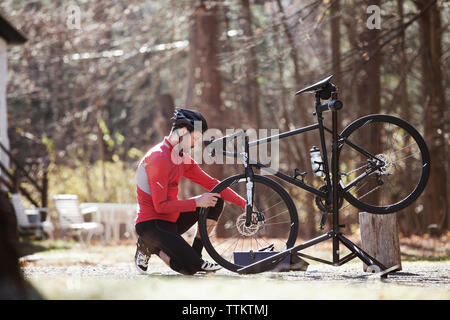 Side view of athlete adjusting bicycle on road during sunny day Stock Photo