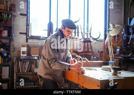 Confident carpenter planning wood on table in workshop Stock Photo